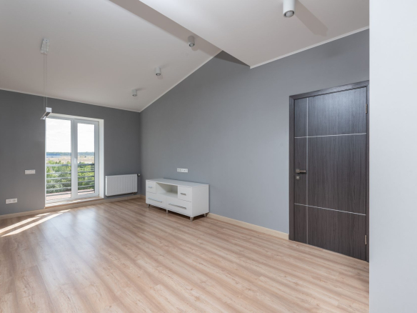 Bright and empty modern room with hardwood floors and large window view.