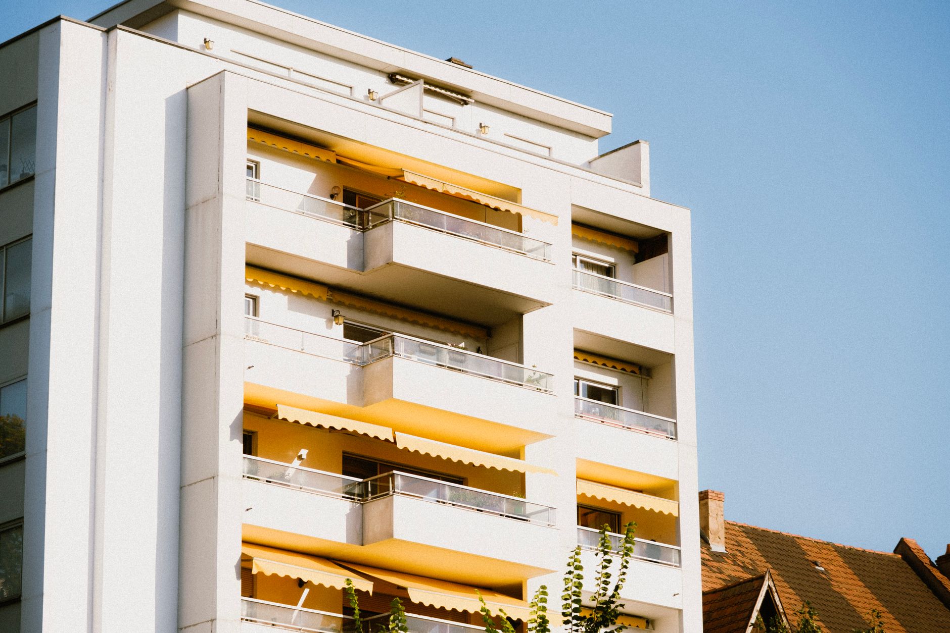 Low-angle view of a contemporary apartment building with yellow balconies against a clear sky.