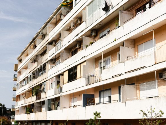Multi-story apartment building with balconies on a sunny day.