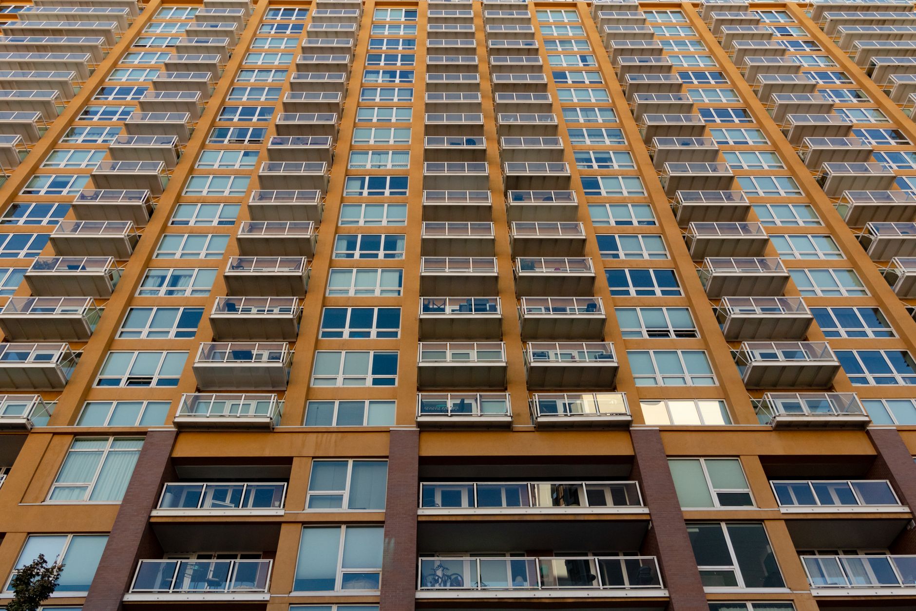 Expansive view of a modern skyscraper with glass balconies and windows, captured in daylight.