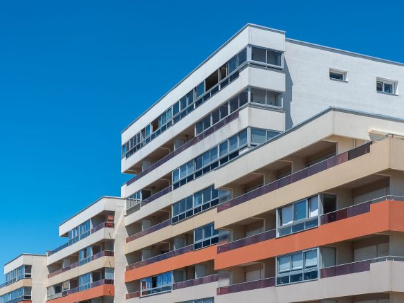 Contemporary multi-story apartment buildings with balconies under a clear blue sky, showcasing modern architecture.