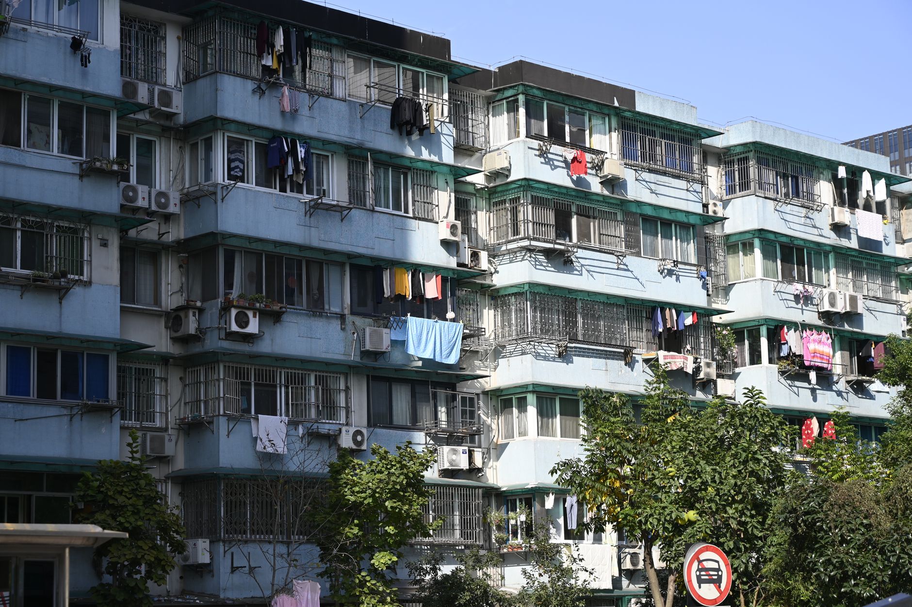 Exterior view of urban apartments with laundry hanging outside on balconies under a clear sky.
