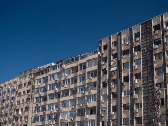 Visoke stambene zgrade sa klima uređajima pod vedrim nebom – ilustracija uz tekst o stanu sa garažom