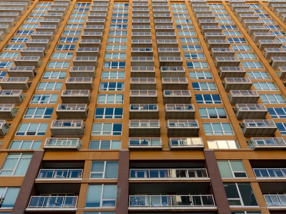 Expansive view of a modern skyscraper with glass balconies and windows, captured in daylight.