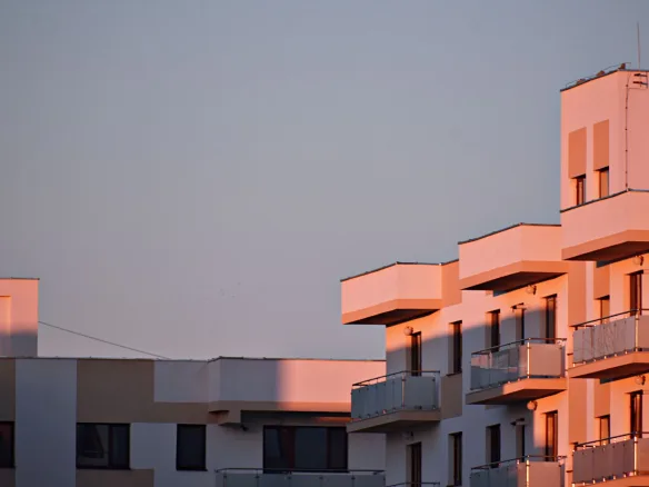 Modern apartment building with balconies bathed in sunset light.