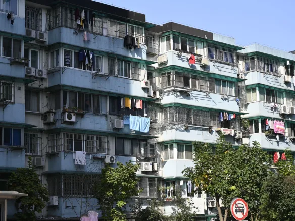 Exterior view of urban apartments with laundry hanging outside on balconies under a clear sky.
